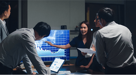Business team reviewing a chart on a screen, engaged in discussion and analysis.