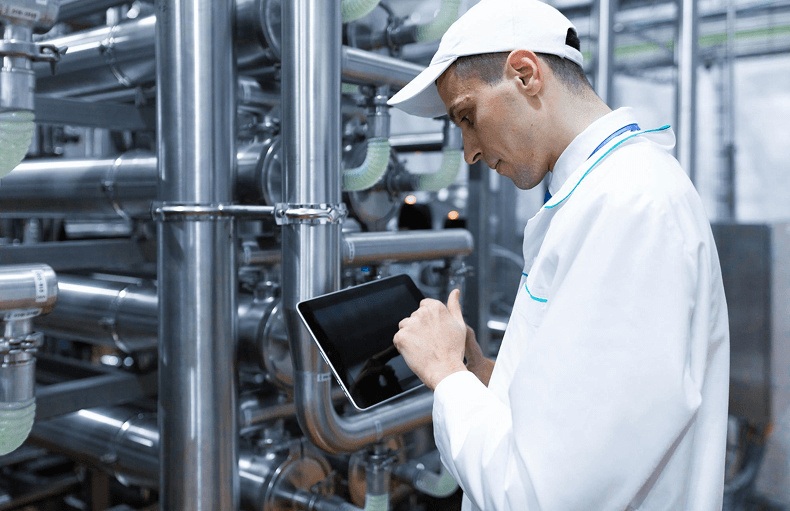 A man dressed in a white coat is engaged with a tablet, indicating a focus on technology in a professional environment.